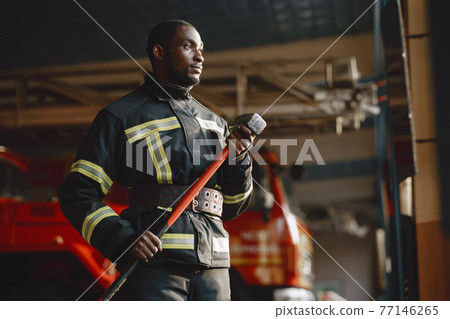 Portrait of a firefighter standing in front of a fire engine 77146265