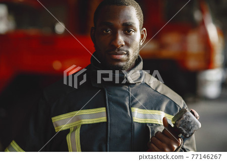 Portrait of a firefighter standing in front of a fire engine Portrait of a firefighter standing in front of a fire engine 77146267