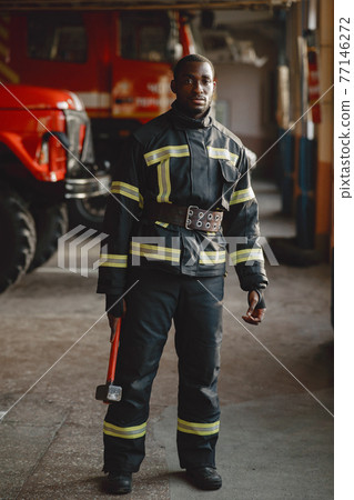 Portrait of a firefighter standing in front of a fire engine 77146272
