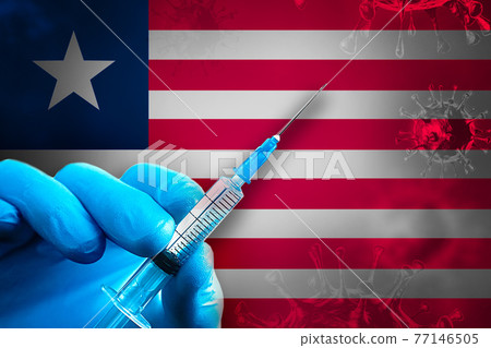 Liberia Covid-19 Vaccination Campaign. Hand in a blue rubber glove holds a syringe with covid-19 virus vaccine in front of Liberia flag 77146505