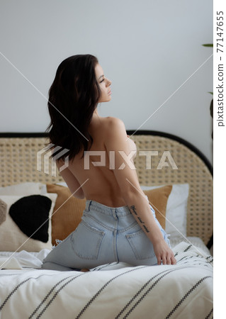 Topless woman touching breast in bedroom 77147655