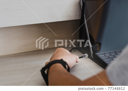 Man hand connecting internet cable wire to laptop. 77148812