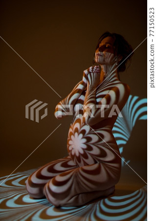 Nude pregnant woman in dark with ornamental shadows on body 77150523