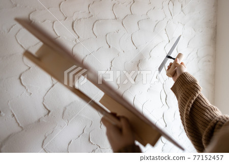 A young woman painting the walls of a new single-family home under construction with diatomaceous earth A young woman painting the walls of a new single-family home under construction with diatomaceous earth 77152457
