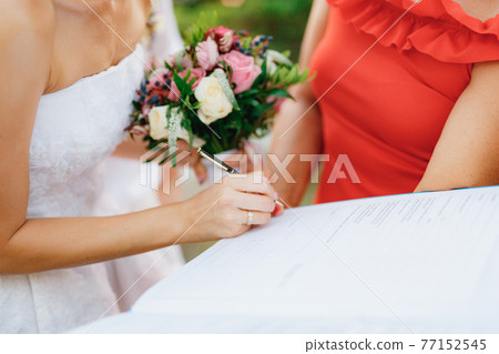 The bride signs the wedding certificate during the wedding ceremony, close-up.  77152545