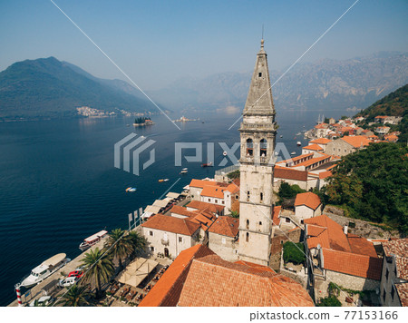 The bride and groom looks out from the window of the ancient tower in the old town of Perast  77153166