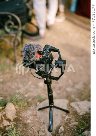 Black digital camera stands on a tripod on stones. View from above 77153177