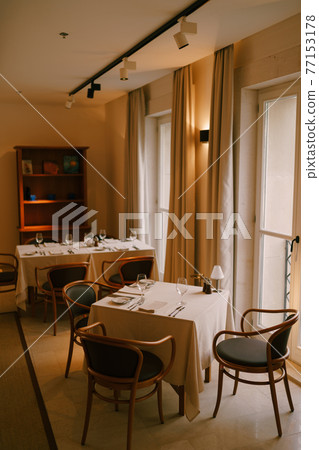 Cozy classic interior of the restaurant, tables are by the window. 77153178