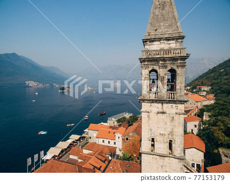 The bride and groom hug in the window of the ancient tower in the old town of Perast  77153179