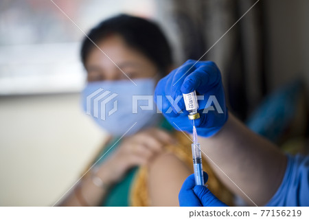 Doctor injecting vaccine into arm of patient Doctor injecting vaccine into arm of patient 77156219