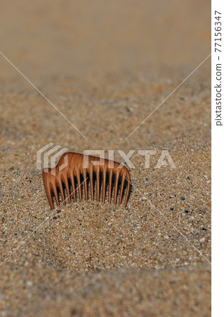 Handmade wooden comb of pear tree for scalp massage and aroma combing on the beach in sand. 77156347