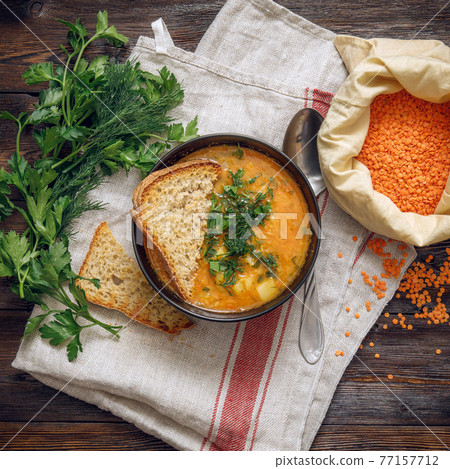 Homemade lentil cream soup with crispbread and parsley on wooden table 77157712