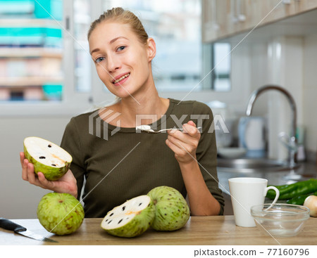 Happy young woman with chirimoya fruit at home kitchen Happy young woman with chirimoya fruit at home kitchen 77160796