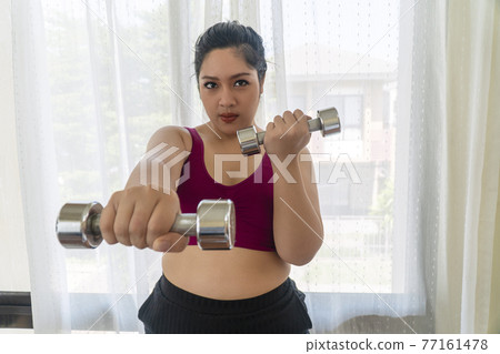 Positive happy overweight fat woman holding dumbbells in own hands workout dieting weight loss Positive happy overweight fat woman holding dumbbells in own hands workout dieting weight loss 77161478