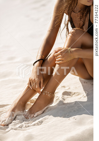 Woman Sitting on the Beach With Bracelets Woman Sitting on the Beach With Bracelets 77164222