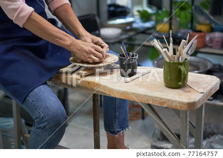 Love pottery. Close up shot of hands of mature woman shaping, creating handmade clay ceramic bowl in pottery workshop studio 77164757