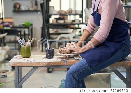 Handmade. Cropped shot of mature woman in apron shaping, creating clay ceramics in pottery workshop studio Handmade. Cropped shot of mature woman in apron shaping, creating clay ceramics in pottery workshop studio 77164760