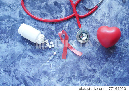 Red ribbon HIV, and stethoscope on black background. 77164920