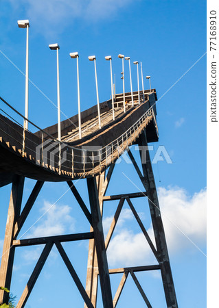 Abandoned wooden ski jumping hill on blue sky background in Kouvola, Finland Abandoned wooden ski jumping hill on blue sky background in Kouvola, Finland 77168910