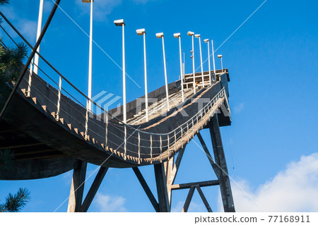 Abandoned wooden ski jumping hill on blue sky background in Kouvola, Finland Abandoned wooden ski jumping hill on blue sky background in Kouvola, Finland 77168911