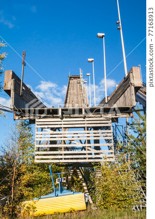 Abandoned wooden ski jumping hill on blue sky background in Kouvola, Finland Abandoned wooden ski jumping hill on blue sky background in Kouvola, Finland 77168913