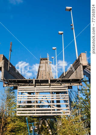 Abandoned wooden ski jumping hill on blue sky background in Kouvola, Finland Abandoned wooden ski jumping hill on blue sky background in Kouvola, Finland 77168914