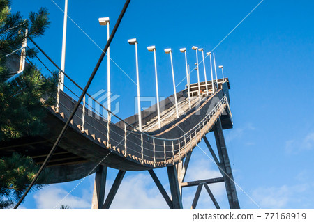 Abandoned wooden ski jumping hill on blue sky background in Kouvola, Finland Abandoned wooden ski jumping hill on blue sky background in Kouvola, Finland 77168919