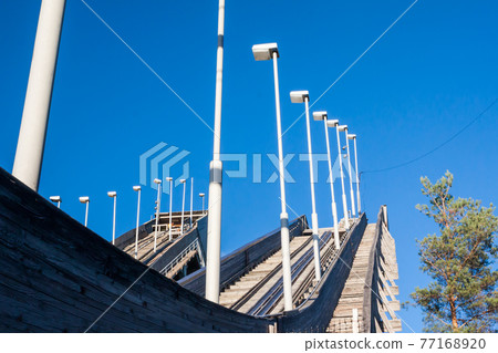 Abandoned wooden ski jumping hill on blue sky background in Kouvola, Finland 77168920
