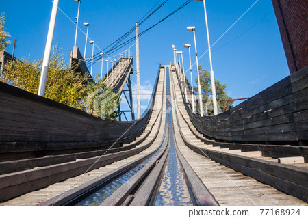 Abandoned wooden ski jumping hill on blue sky background in Kouvola, Finland Abandoned wooden ski jumping hill on blue sky background in Kouvola, Finland 77168924