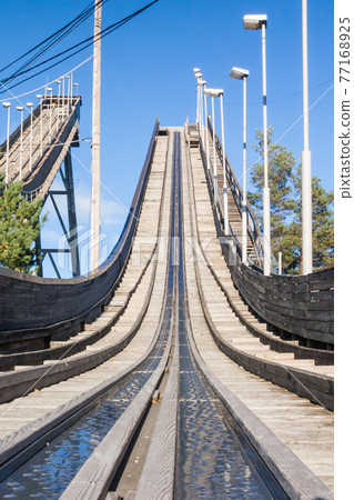 Abandoned wooden ski jumping hill on blue sky background in Kouvola, Finland 77168925