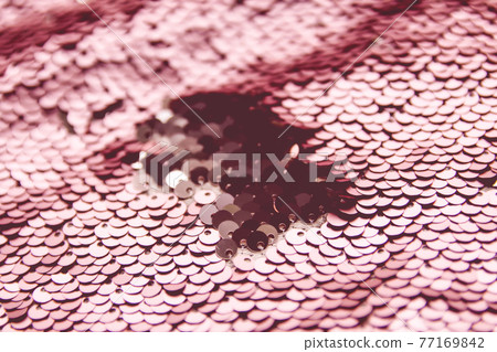 Bright shiny texture of colorful sequins in warm colors. Fashion fabric background. 77169842