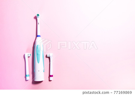 Two electrical toothbrushes on a soft light pink background Two electrical toothbrushes on a soft light pink background 77169869