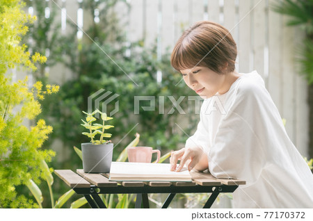 Young woman reading over coffee on the terrace 77170372