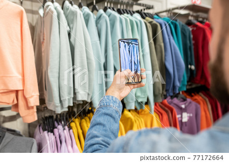 A person taking photo of new fashion collection in a store 77172664