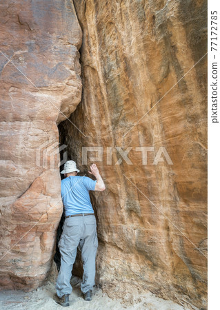 hiker exploring a tight slot canyon hiker exploring a tight slot canyon 77172785