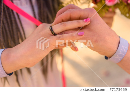 bride and groom exchange rings during the wedding ceremony 77173669