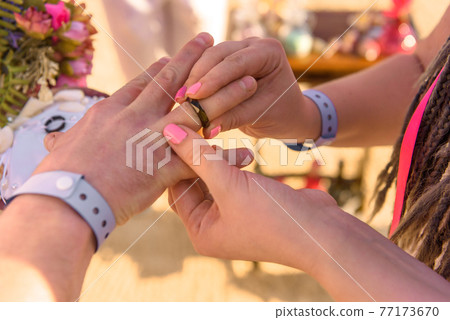 bride and groom exchange rings during the wedding ceremony 77173670