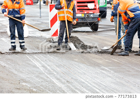 The road workers are cleaning the road on the fenced section of the carriageway. The road workers are cleaning the road on the fenced section of the carriageway. 77173813