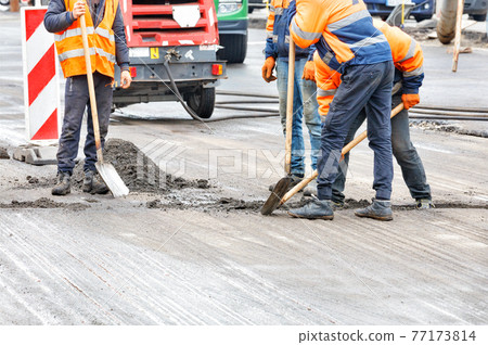 Road workers are shoveling the old road surface on the roadway. Road workers are shoveling the old road surface on the roadway. 77173814