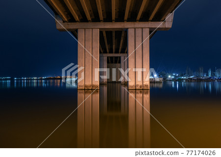 Night city view, luminous buildings and bridge. Bottom view. Ukraine. Nikolaev. Night city view, luminous buildings and bridge. Bottom view. Ukraine. Nikolaev. 77174026
