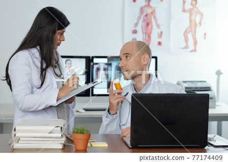 Doctors discussing pills Doctors discussing pills 77174409