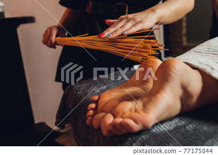 massage of female feet with bamboo sticks. massage of female feet with bamboo sticks. 77175844