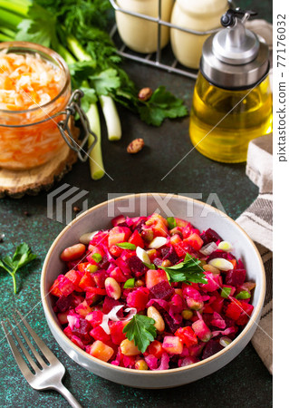 Beetroot salad vinaigrette with pickled cucumber, beans, carrots, peas, sauerkraut on a dark countertop. 77176032