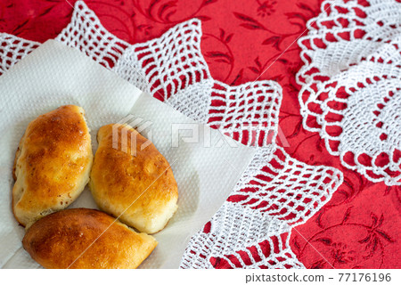 Baked homemade pies on a plate with a lace napkin Baked homemade pies on a plate with a lace napkin 77176196