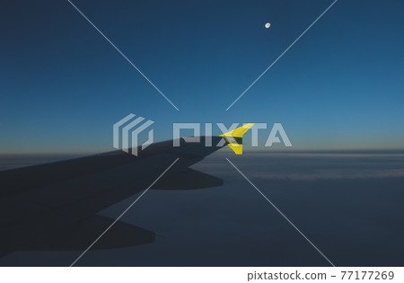View of the moon and the wing from the window of a flying plane. 77177269