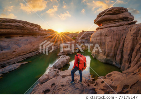Back of tourist man, a backpacker people, travel in Sam Phan Bok, Ubon Ratchathani, Thailand. Dry rock with mountain hills. Nature landscape. Grand Canyon of Thailand. Adventure lifestyle activity. 77178147