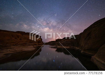 Sam Phan Bok with milky way and stars at night, Ubon Ratchathani, Thailand. Dry rock reef in the Mekong River with mountain hills. Nature landscape background. Grand Canyon of Thailand. Sam Phan Bok with milky way and stars at night, Ubon Ratchathani, Thailand. Dry rock reef in the Mekong River with mountain hills. Nature landscape background. Grand Canyon of Thailand. 77178156