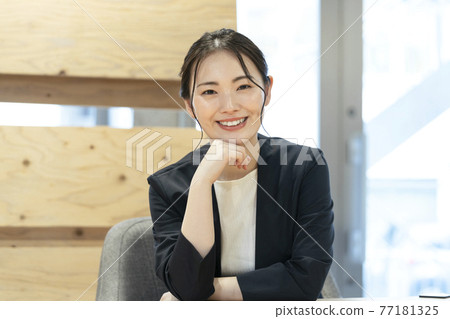 A business woman in her twenties smiling looking at the camera 77181325