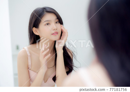 Beautiful young asian woman smiling look at mirror of checking face with skin care and cosmetic. Beautiful young asian woman smiling look at mirror of checking face with skin care and cosmetic. 77181756