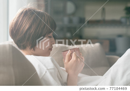 少婦坐沙發和飲用的咖啡 77184469
